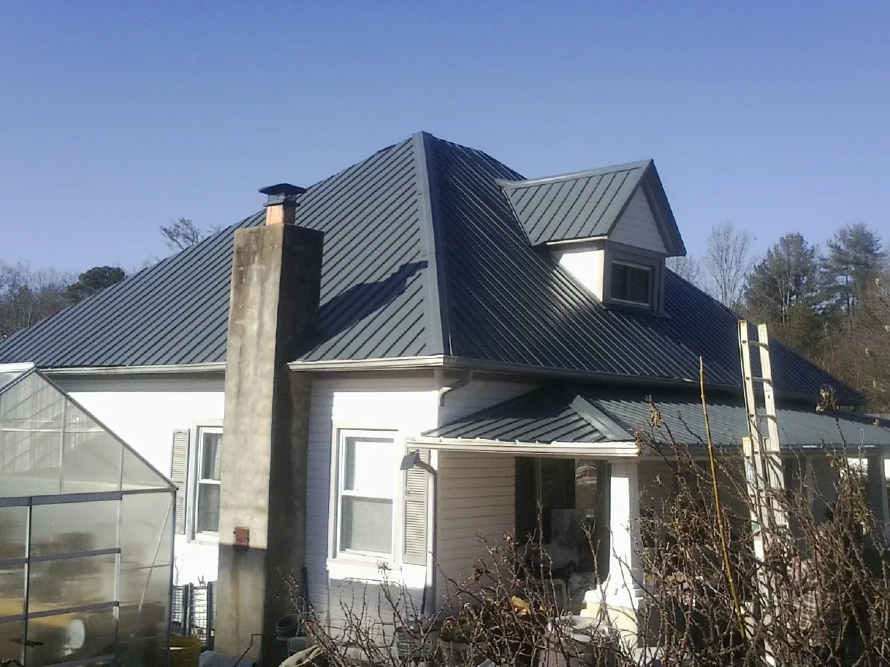 Dark blue standing seam metal roof on a white farmhouse with dormer — Slate & Tile Roof Repair by Roofing Brothers in Finger
