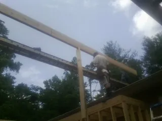 Carpenter setting a ridge beam over a new addition frame — Ice Dam Removal by Roofing Brothers in Finger