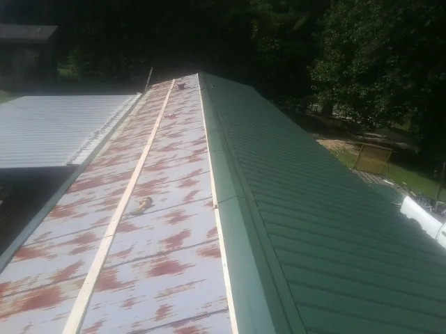 Old rusted panels beside newly installed green metal roofing — Wind Damage Roof Repair by Roofing Brothers in Finger