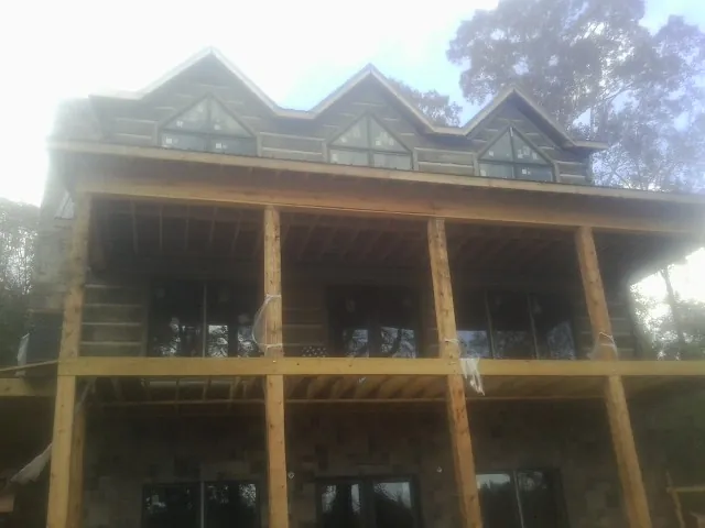 Dormers and porch framing on a large log home under construction — Roof Coating work by our crew in Finger