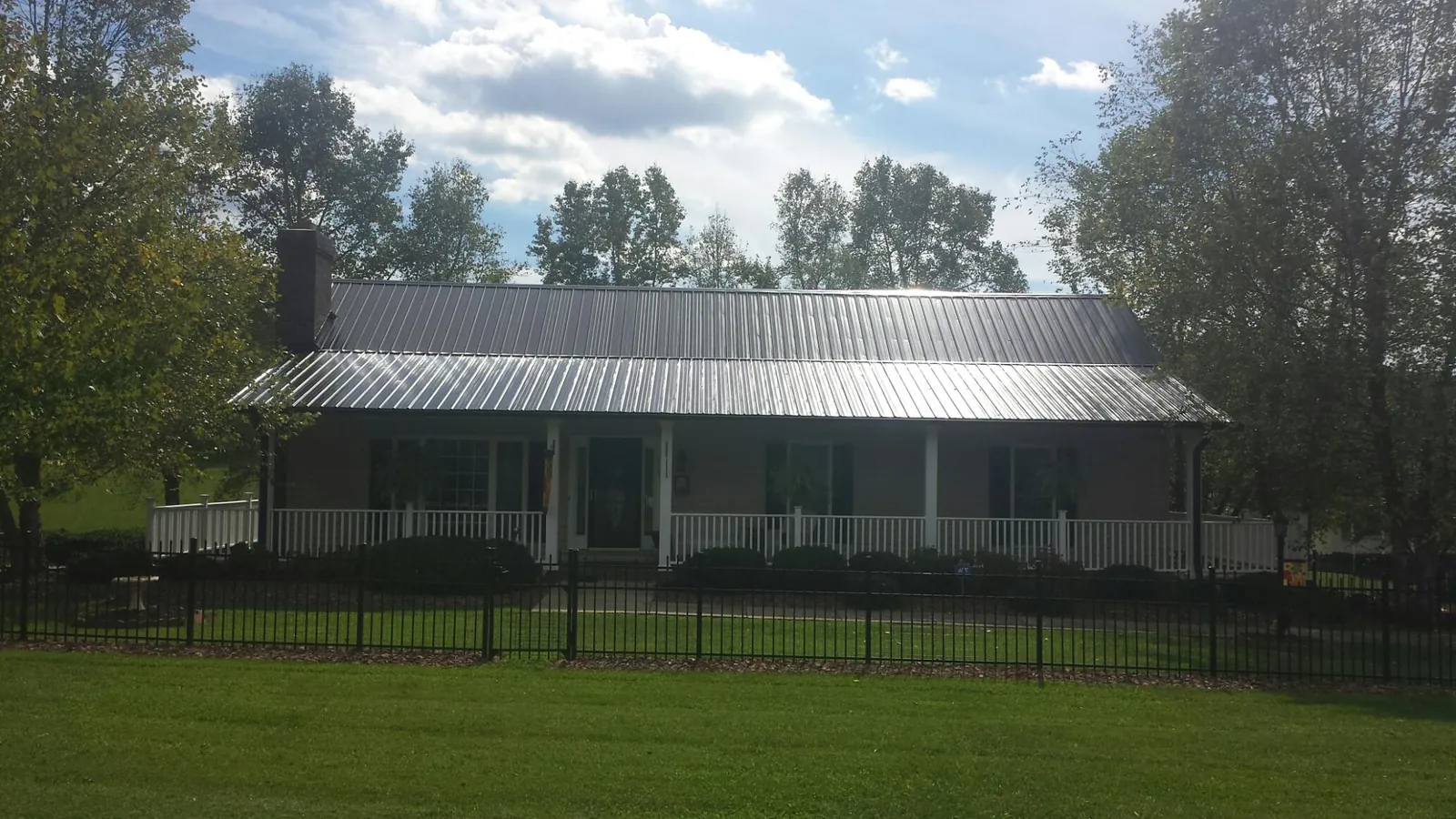 Gray metal roof on a brick ranch with a full width front porch — Gutter Guard Installation work by our crew in Finger