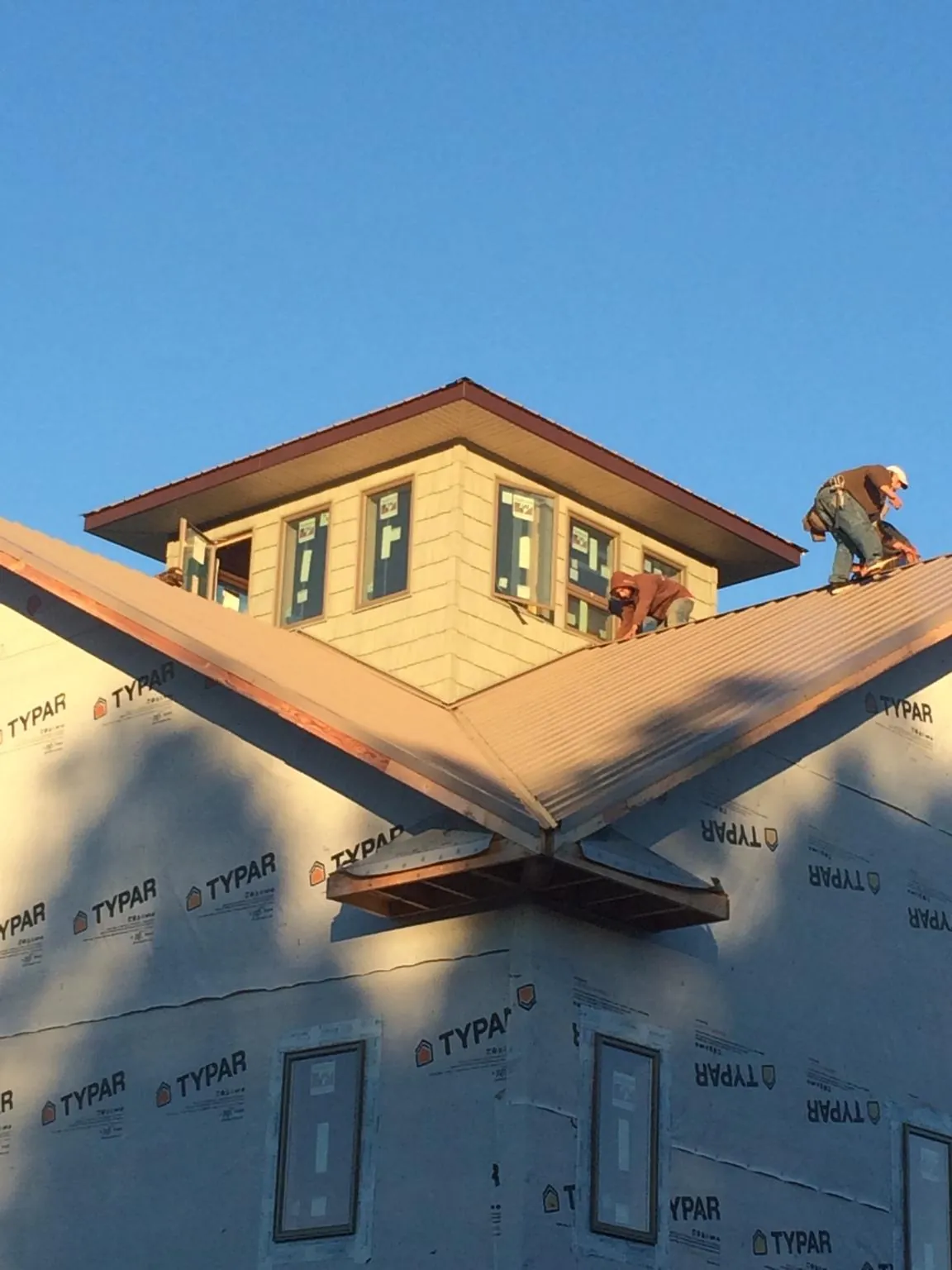 Roofers working around a rooftop cupola on a new metal roof at sunset — Roof Waterproofing in Finger by Roofing Brothers